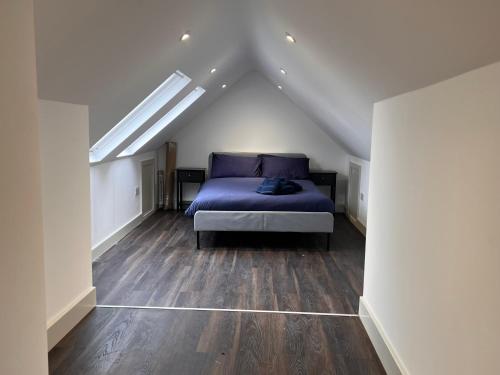 a bedroom with a blue bed in a attic at Star London Finchley Road 3-Bed Abode in London