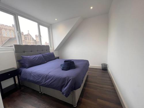 a bedroom with a bed with purple sheets and two windows at Star London Finchley Road 3-Bed Abode in London