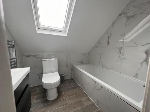 a bathroom with a toilet and a tub and a sink at Star London Finchley Road 3-Bed Abode in London