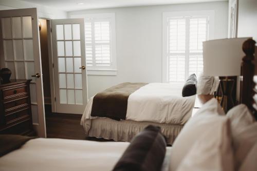 a bedroom with two beds and two windows at The Jefferson Inn in Southern Pines