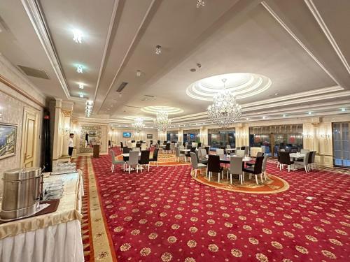 une salle de banquet avec des tables et des chaises sur un tapis rouge dans l'établissement Modern Hotel, à Baku