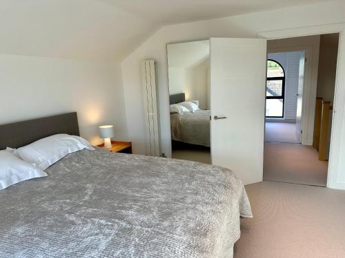 a bedroom with a large bed and a mirror at ALTIDO Stylish house with patio in Devon in Ipplepen