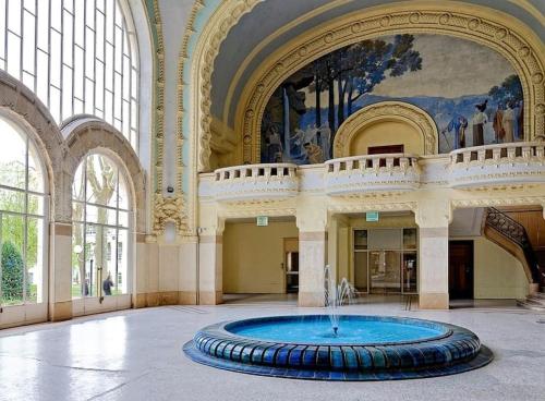 a large room with a fountain in the middle of a building at La Villa des Oiseaux - Coeur de Vichy in Vichy