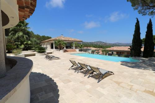 une terrasse avec des chaises longues et une piscine dans l'établissement villa saint paul, à Sainte-Maxime