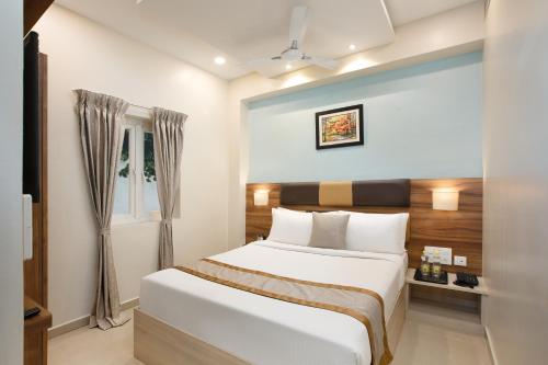 a bedroom with a white bed and a window at Grande Inn Trichy in Tiruchchirāppalli