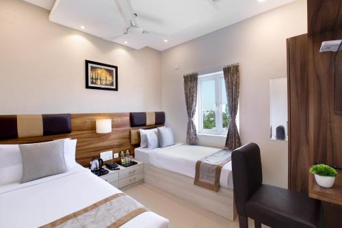 Habitación de hotel con 2 camas y escritorio en Grande Inn Trichy, en Tiruchchirāppalli