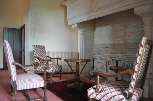 two chairs and a table in a room with a fireplace at Château de Bouesse en Berry in Bouesse