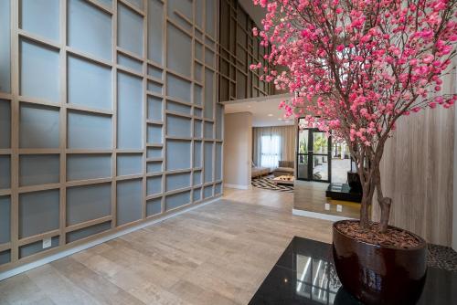 a hallway with a tree in a vase with pink flowers at Liberdade SP a 250m do metrô in Sao Paulo