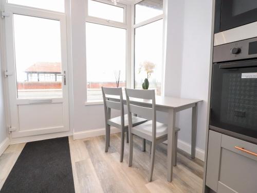 a kitchen with a table and chairs and a window at Ferry View in Fleetwood