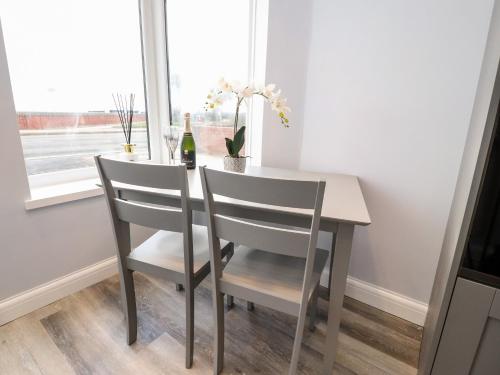 a dining room table with two chairs and a bottle of wine at Ferry View in Fleetwood