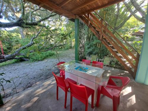 una mesa y sillas rojas en un patio en Casa Estilosa e Rústica com Vista para o Pôr do Sol da Ilha do Mel!, en Convento