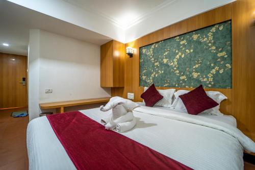 a hotel room with a bed with a stuffed animal on it at Hotel Kewal in Nashik