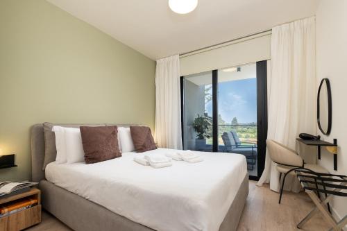 a bedroom with a large white bed and a balcony at Sunset Gardens in Limassol