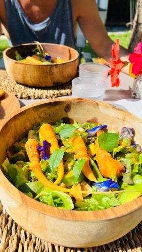 a wooden bowl filled with a salad on a table at Île tropical lodges in Sainte-Anne