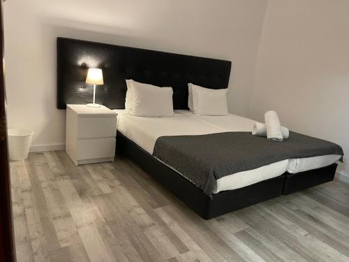 a bedroom with a large bed with a black headboard at Residencial Mar e Sol in Costa da Caparica