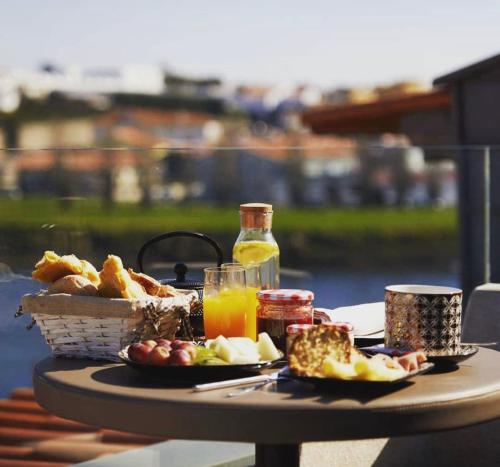 a table with food and a basket of bread and juice at Casa do Rio charm suites in Vila do Conde