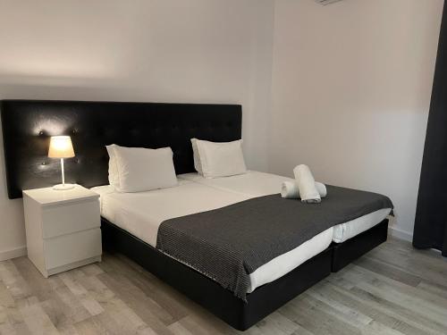 a bedroom with a large bed with a black headboard at Residencial Mar e Sol in Costa da Caparica