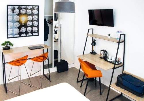メゾン・アルフォールにあるTwenty Business Flats Maisons Alfort Les Juilliottesのデスク2台とオレンジの椅子が備わる客室です。