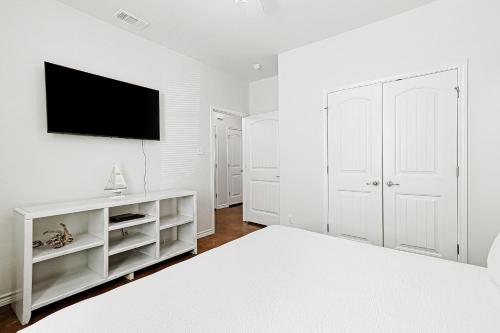 a white bedroom with a bed and a flat screen tv at Nemo Cay - Endless Summer I in Padre Island