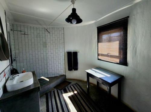 baño con lavabo, espejo y ventana en Kwelanga River Lodge, en Vioolsdrift