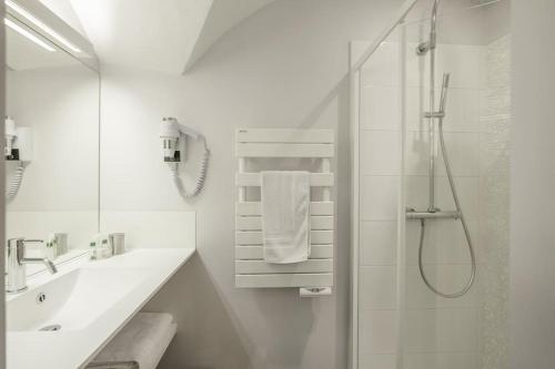 une salle de bain blanche avec une douche et un lavabo dans l'établissement Aya, appartement moderne dans le cœur du village, au Monêtier-les-Bains