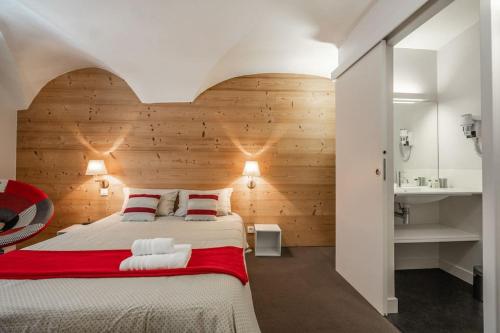 une chambre avec un grand lit avec un mur en bois dans l'établissement Aya, appartement moderne dans le cœur du village, au Monêtier-les-Bains