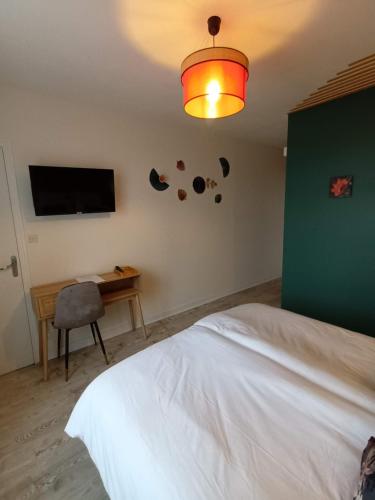 sypialnia z łóżkiem, biurkiem i telewizorem w obiekcie Les chambres de la Vallée w mieście Argenton-Château