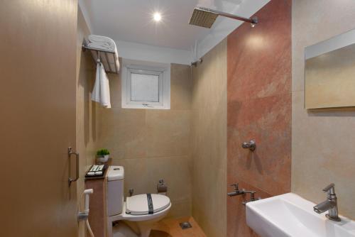 a bathroom with a toilet and a sink and a mirror at Grande Inn Trichy in Tiruchchirāppalli
