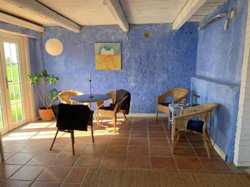una stanza con tavolo, sedie e parete blu di Strandbadsgården B&B a Löderup