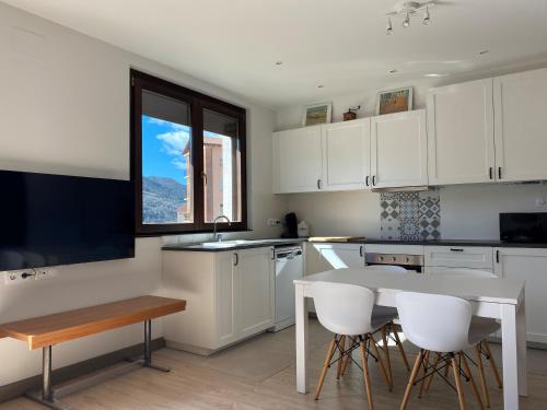 a kitchen with white cabinets and a table and chairs at Apartamento acogedor in Sant Joan de les Abadesses