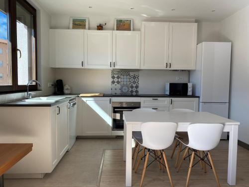 a kitchen with white cabinets and a table and chairs at Apartamento acogedor in Sant Joan de les Abadesses