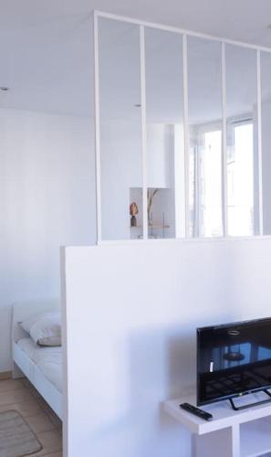 Cette chambre blanche comprend un lit et une télévision. dans l'établissement T2 aménagé Palais Longchamp, à Marseille