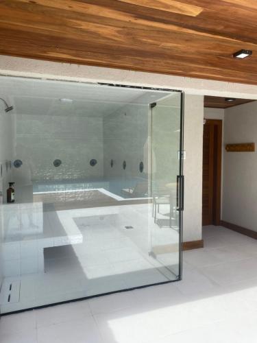 una puerta de pivote de cristal en una habitación con techo en Casa alto padrão a 100 metros da praia brava, en Búzios