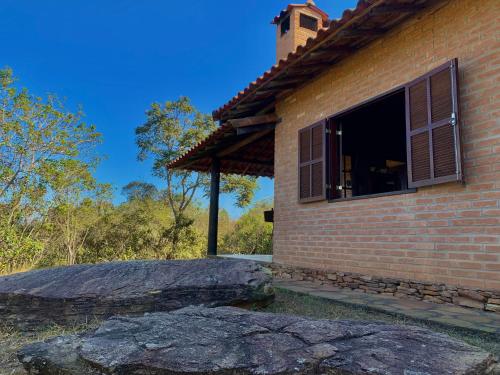 une maison en briques avec une fenêtre et un gros rocher dans l'établissement August de Saint Hilaire/ Reserva Alto da Colina, à Conceição da Ibitipoca