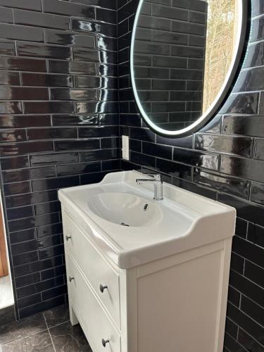 a bathroom with a white sink and a mirror at Leśna Residence & SPA in Pisz