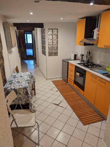 eine Küche mit Orangenschränken, einem Tisch und einem Herd in der Unterkunft APPARTAMENTO CORSi SELF CHECK IN in Parma