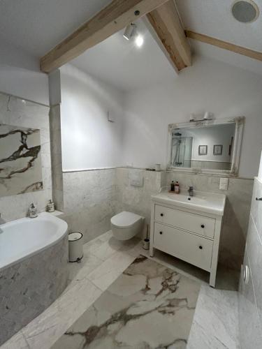 a bathroom with a tub and a toilet and a sink at Leśna Residence & SPA in Pisz