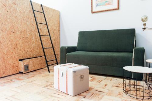 a living room with a green couch and a suitcase at Hostel Pia do Urso in Batalha