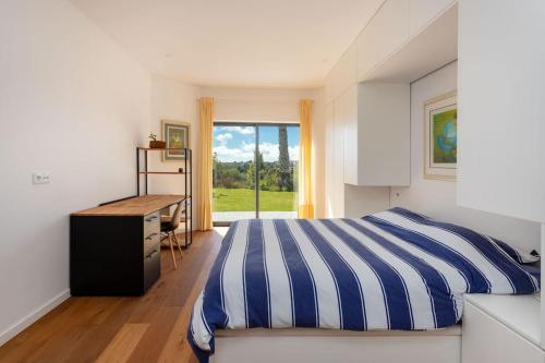 a bedroom with a blue and white striped bed and a desk at Wonderful Villa near Lisbon in São Domingos de Rana
