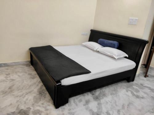 a bed with a black frame and white sheets and pillows at Home to explore Food, History & Shopping in Hyderabad