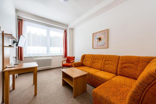 a living room with an orange couch and a table at HOTEL AGRI in Soběšice