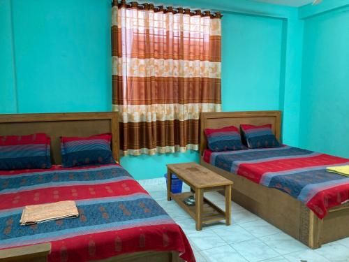 2 łóżka w pokoju z niebieskimi ścianami w obiekcie Hotel Shahin Residential Jatrabari w mieście Dhaka