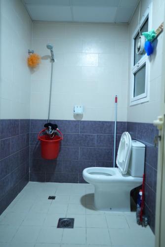 a bathroom with a toilet and a red bucket at Topstay Boys Hostel & Furnished Holiday Home in Dubai