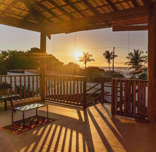 a porch with a bench and the ocean at sunset at Casa Boomerang in Marau