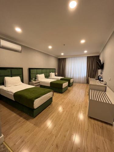 um quarto de hotel com três camas e um sofá em Grand Inn Baku Hotel em Baku