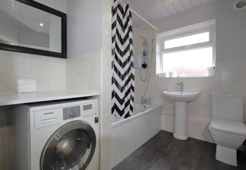 a bathroom with a washing machine and a sink at Cheerful 3 Bedroom 2 Bathroom Bungalow by CozyNest in Earley