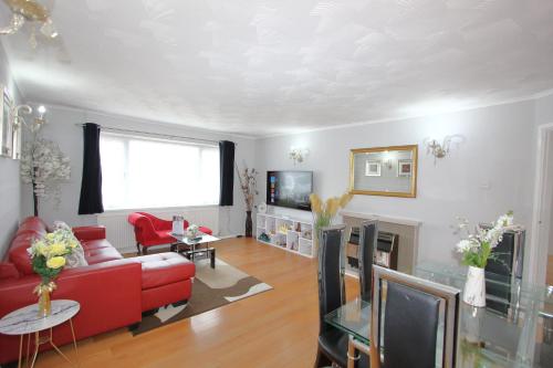 a living room with a red couch and a fireplace at Cheerful 3 Bedroom 2 Bathroom Bungalow by CozyNest in Earley