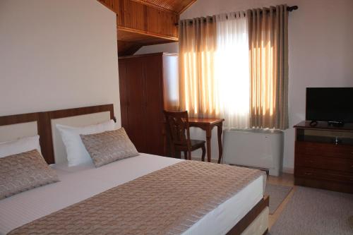 a bedroom with a bed and a television and a desk at Hotel Hasmegaj in Mjedë