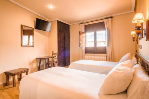 a hotel room with two beds and a window at Hostal Gran Duque in Piedrahita