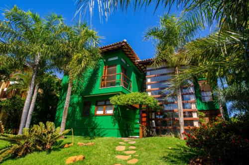 uma casa verde com palmeiras em frente em Quintas de Sauípe - Casa K06 na Costa do Sauípe